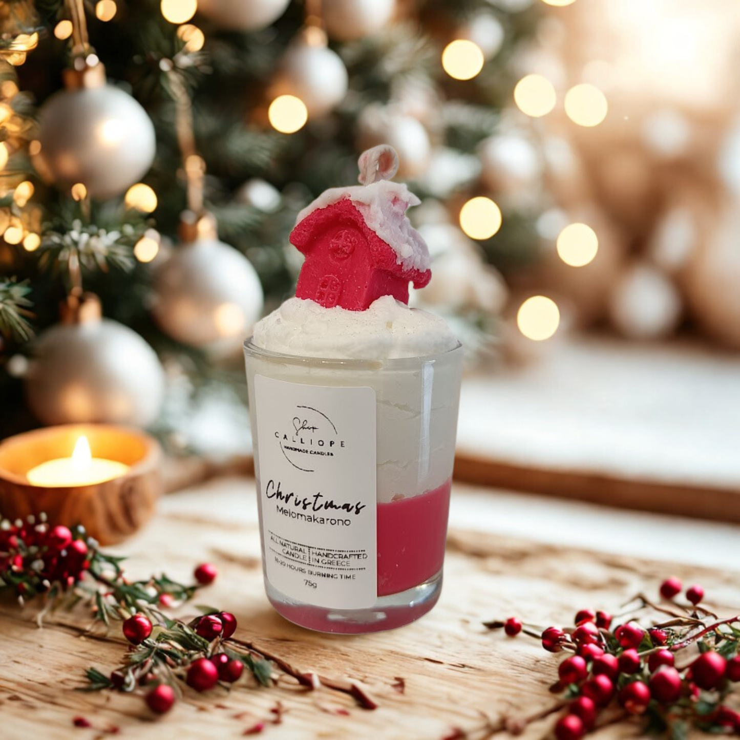 Christmas-themed candle with snowy red house design on top, surrounded by festive decorations.