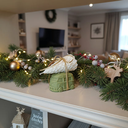 Decorative Christmas garland with lights and ornaments on a mantelpiece in a living room.