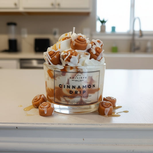 Candle labeled 'Cinnamon Drip' with decorative elements on a kitchen counter.