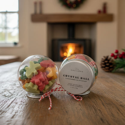 Crystal ball with gingerbread-themed candies on a wooden surface with a fireplace in the background