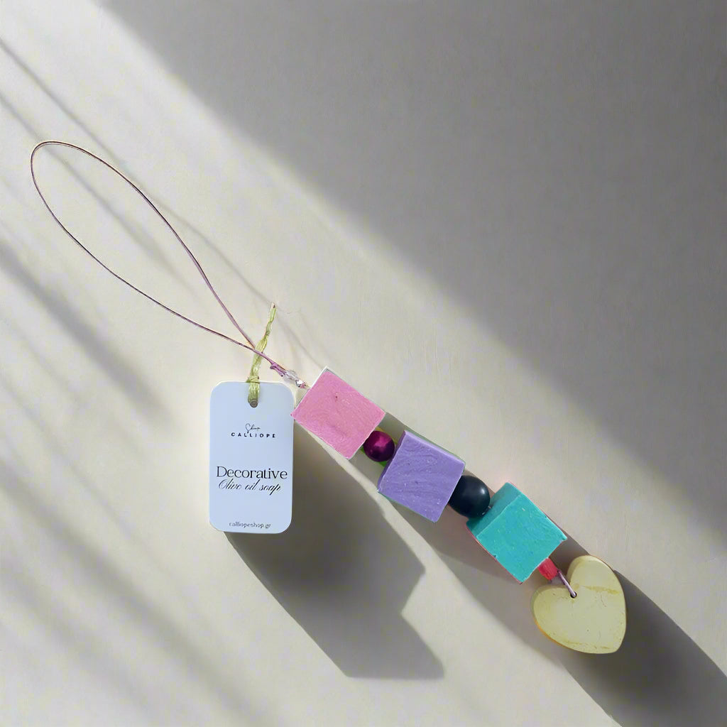 Decorative soap charm with colorful beads and a heart shape on a light gray background