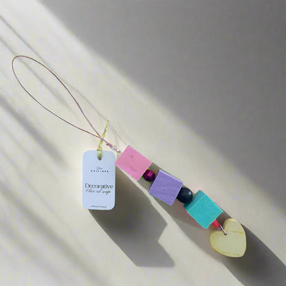 Decorative soap charm with colorful beads and a heart shape on a light gray background