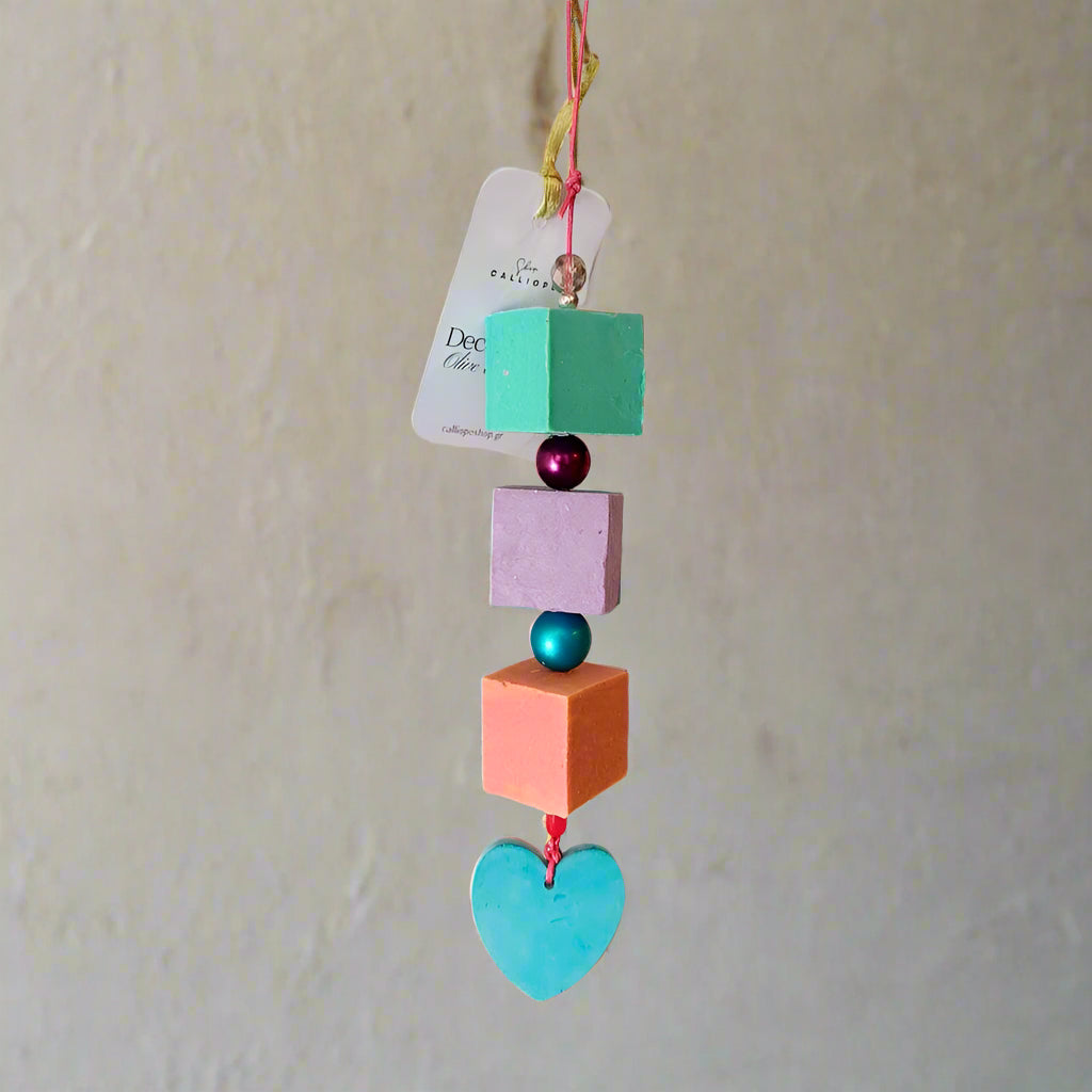 Colorful hanging decorative item with geometric shapes and a heart on a plain background