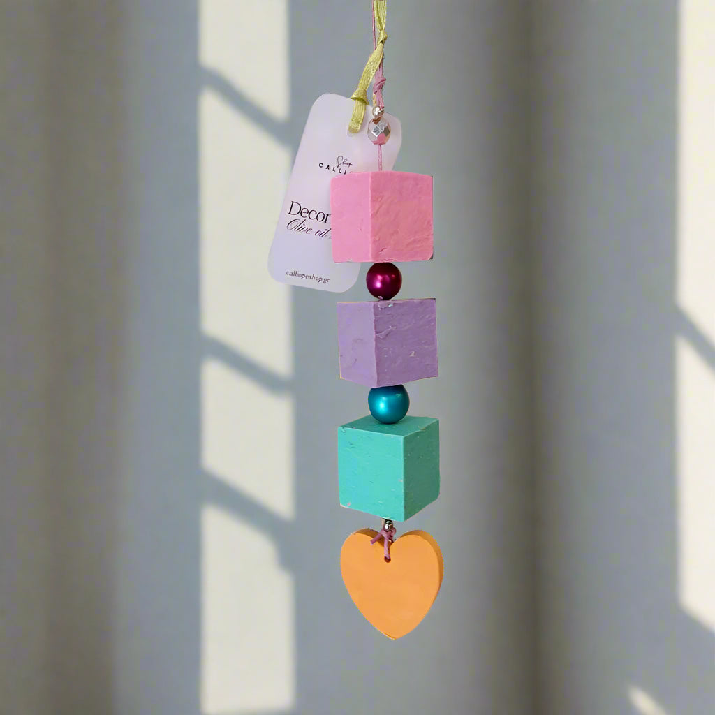 Colorful geometric hanging soap decoration with heart shape on a plain background