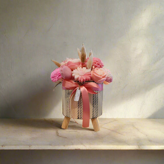 Decorative flower arrangement in a woven basket with pink flowers and ribbons on a marble surface.