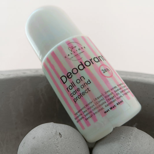 A roll-on deodorant bottle with a white and pink striped label, placed on a surface with a grey rock or stone-like appearance.