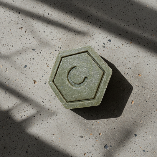 Hexagonal green solid shampoo on a beige surface