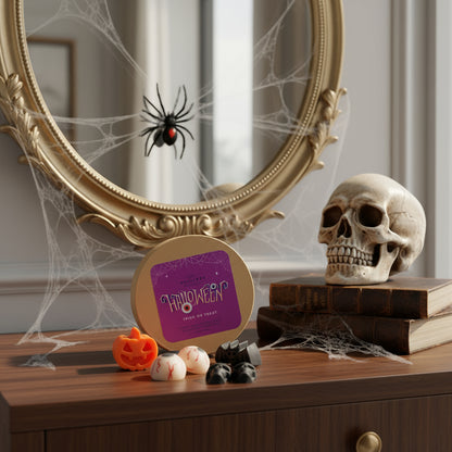 Halloween-themed wax melts in a round craft box, pumpkin-shaped, bat, eyeballs, skuls on a wooden surface, decorated with skul, books, mirror with spider web and spider.
