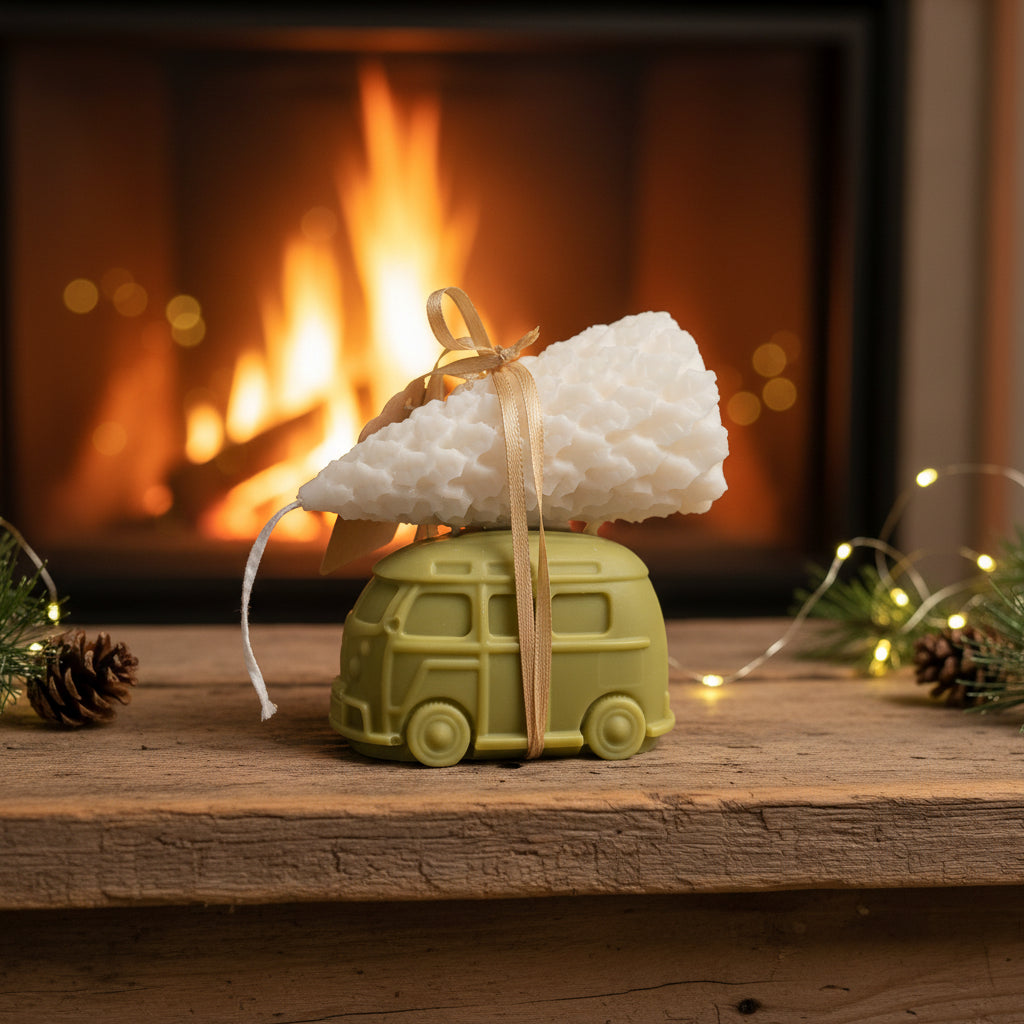 Green van-shaped candle with a white tree on top in front of a fireplace.