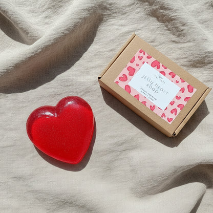 Red heart-shaped jelly soap in clear packaging with a cardboard box featuring a pink heart pattern on a white background.