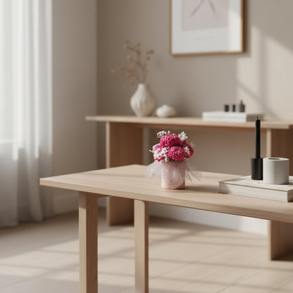 Light wooden table with a candle bouquet of pink flowers in a minimalistic room.