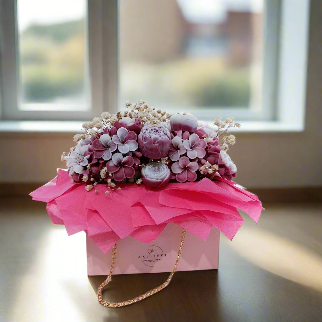 Floral arrangement in a decorative box with pink ribbon on a light background