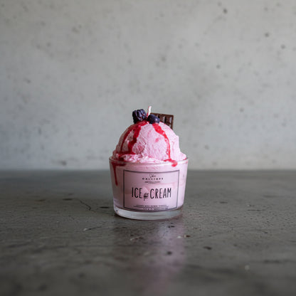 Pink ice cream candle in a container with berries and chocolate on a light surface