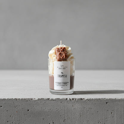 Tiramisu-themed candle in a glass jar on a surface with a dark background