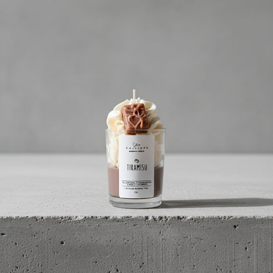 Tiramisu-themed candle in a glass jar on a surface with a dark background