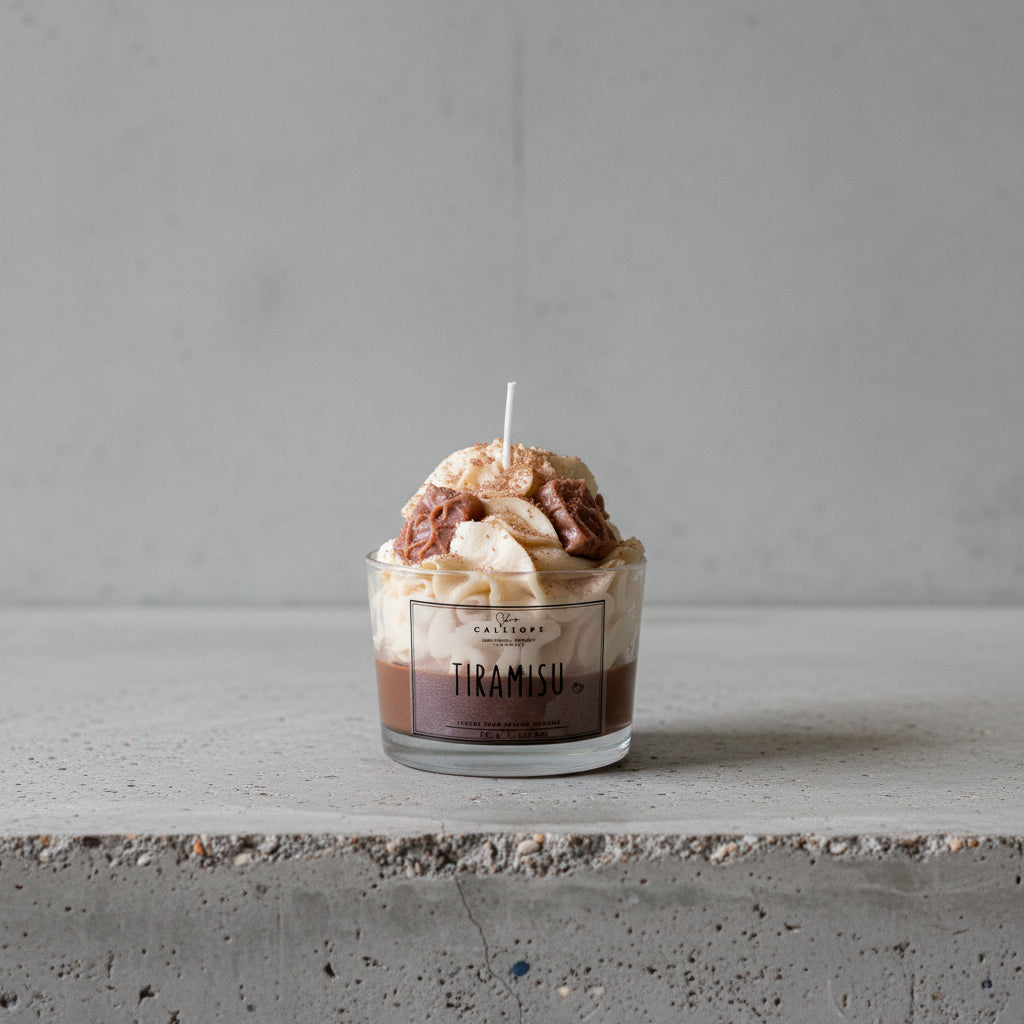 Tiramisu dessert candle in a glass container on a concrete surface.