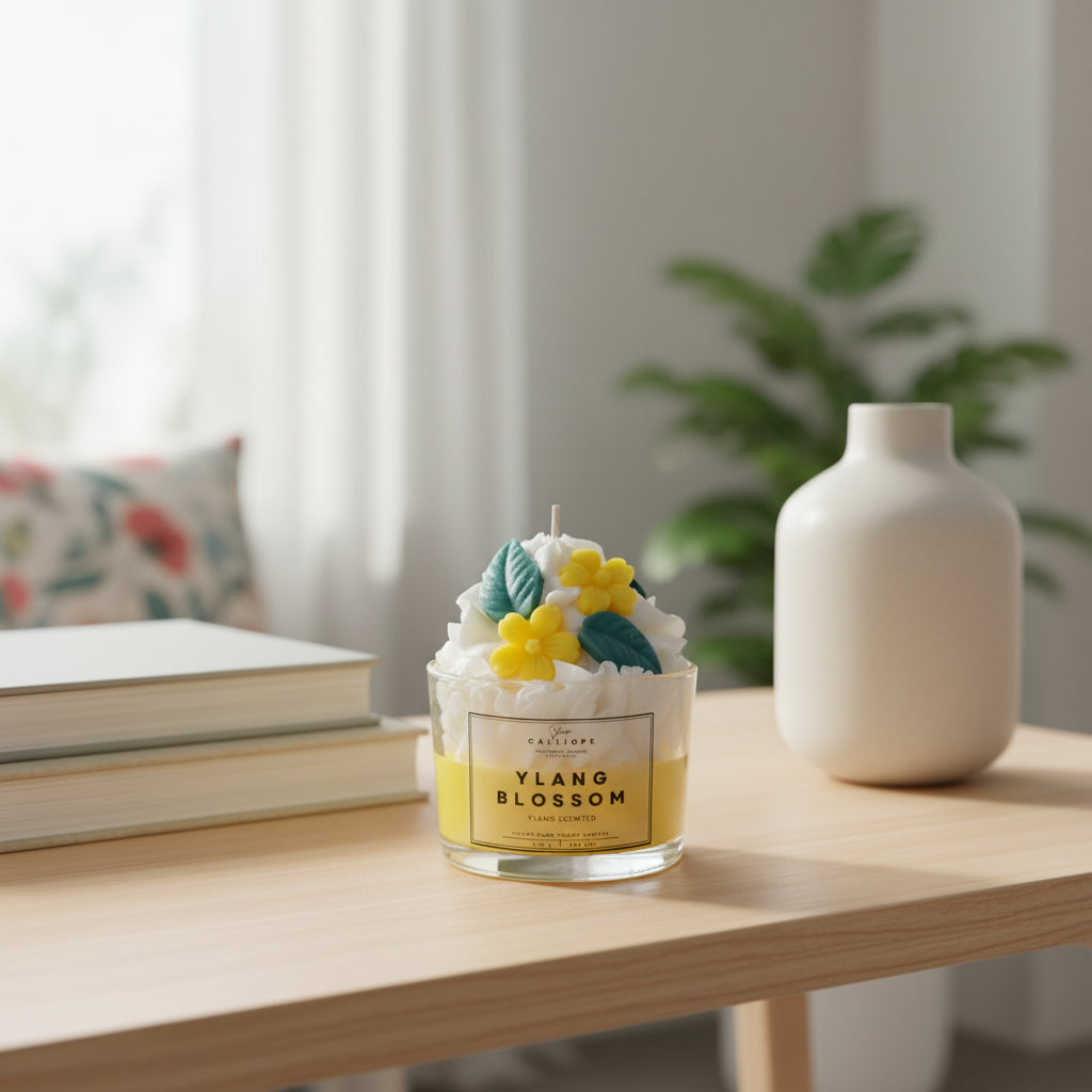 Κερί με ετικέτα “Ylang Blossom” και λουλουδένιες διακοσμήσεις πάνω σε λευκή επιφάνεια.