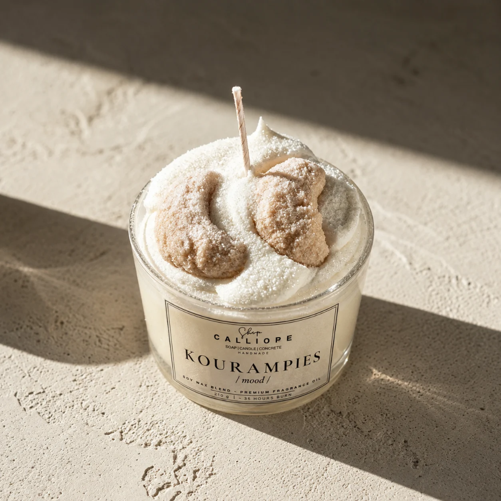 A candle in a clear glass jar with a cream label reading 'Calliope Shop' Kourampies mood!'.