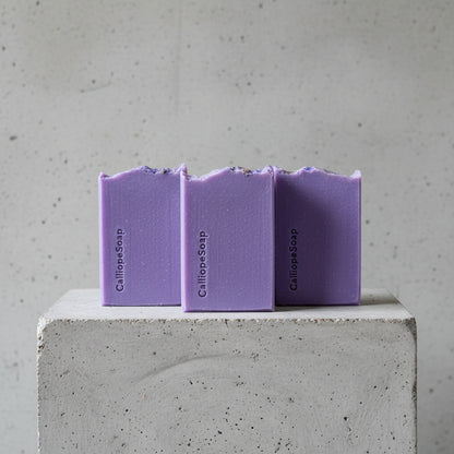 Three bars of purple Calilepe Soap on a grey surface 