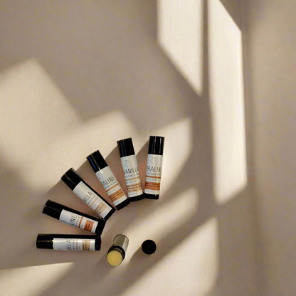 Containers of 'Vanilla & Praline' lip balm with matte black and white labels, positioned on a light background.