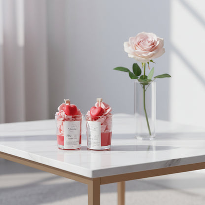 Two small glass containers with heart-shaped candles on a white surface.