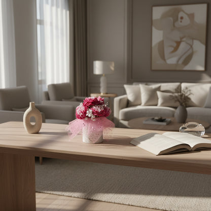 Magenta wax flower bouquet in a silver box with pink tulle placed on a light-toned wooden or cream console in a refined, elegant living room.