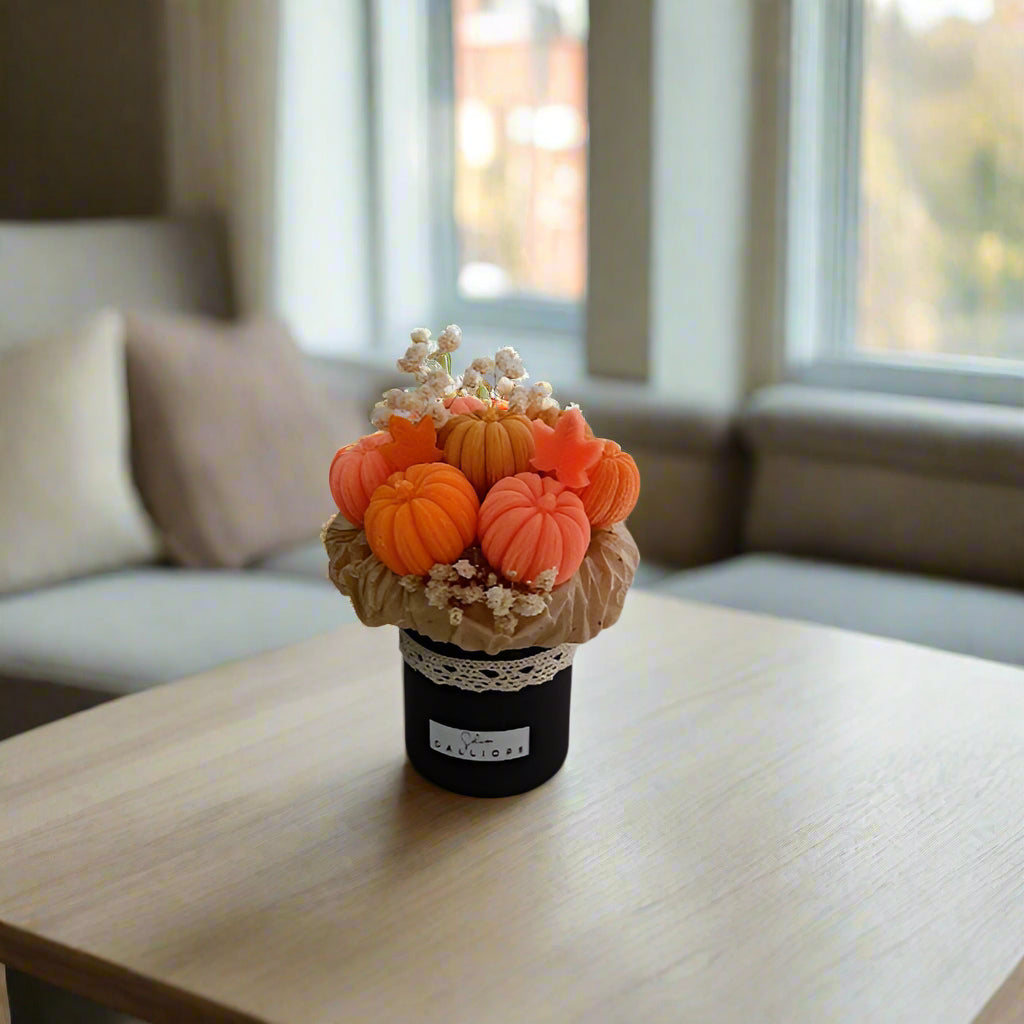 Decorative arrangement of pumpkins in a pot on a white surface with a blue wall in the background.