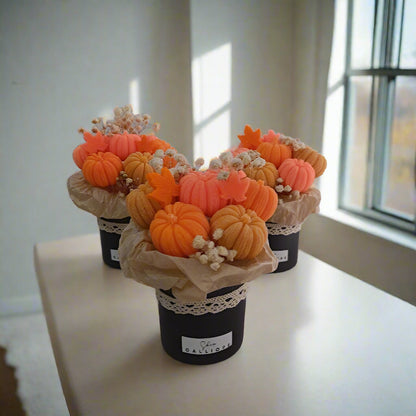 Decorative arrangement of pumpkins in black pots on a white surface.