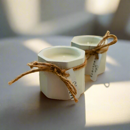 Two hand-painted porcelain candle holders with soy wax candles, tied with twine and tagged with labels.