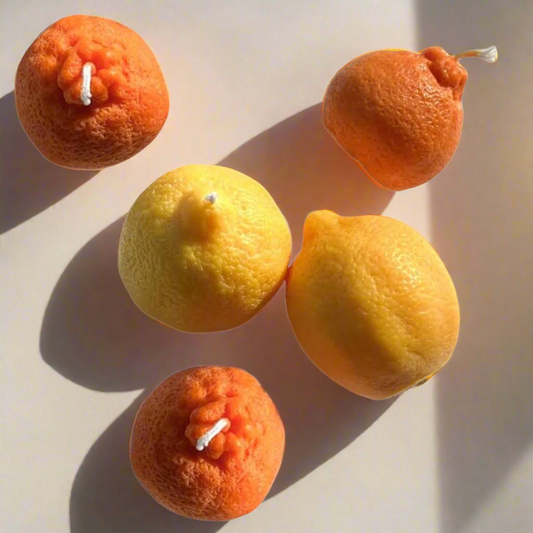 Candles shaped like oranges and lemons on a white background