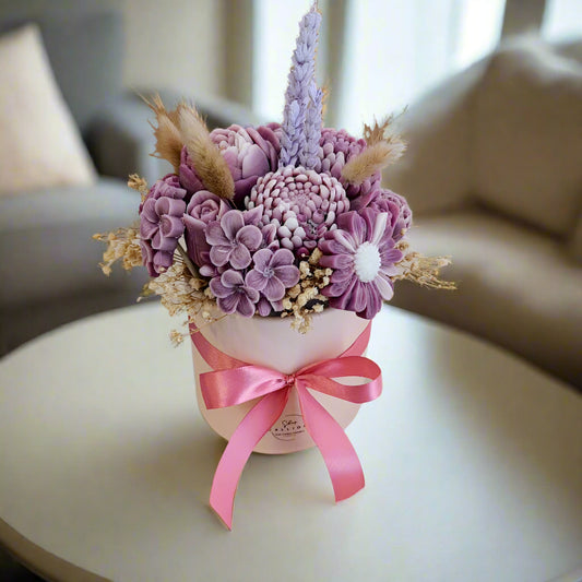 Decorative flower arrangement with a pink ribbon on a white surface