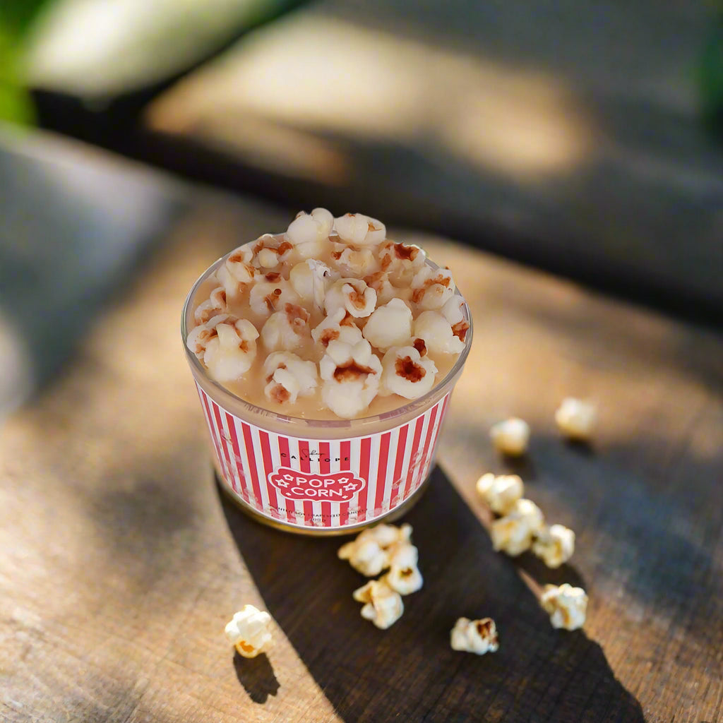 Cup of popcorn with a striped container on a wooden surface