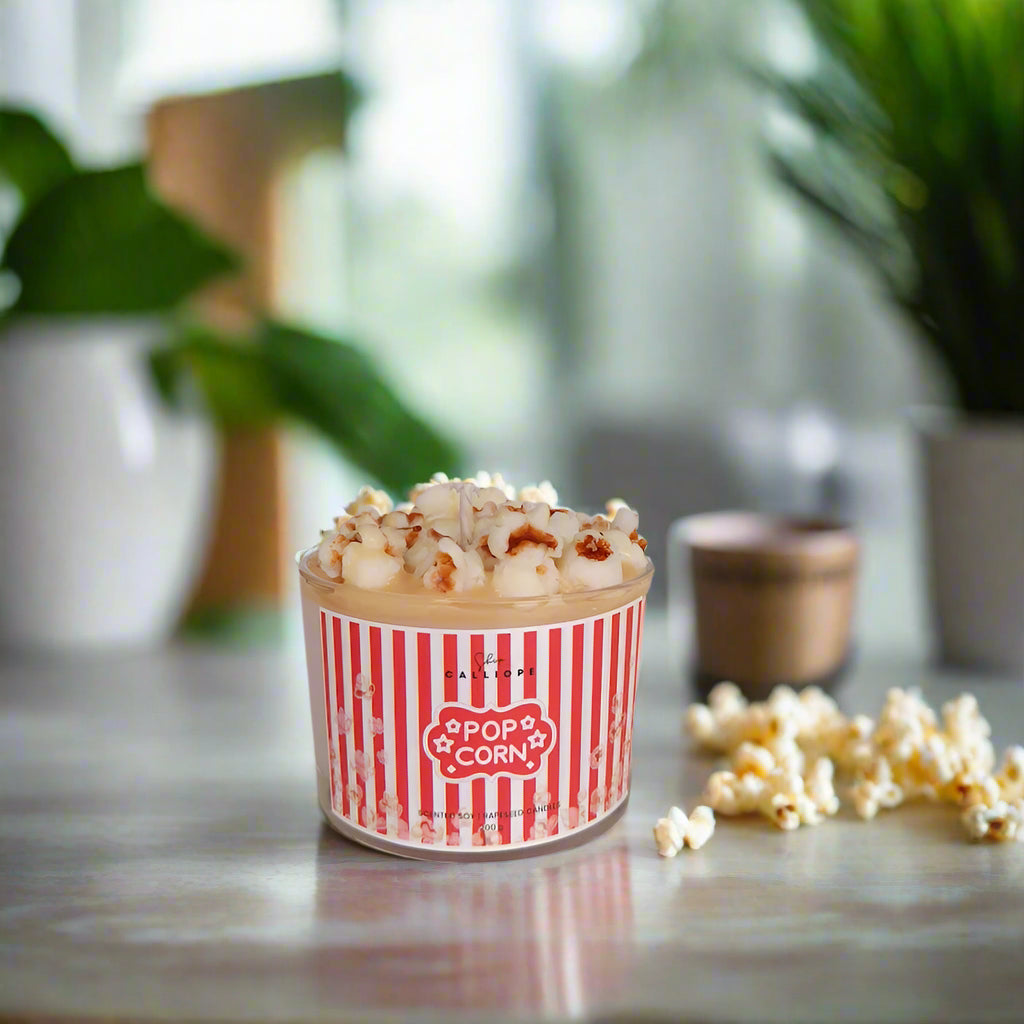 Popcorn in a red and white striped container on a table with plants in the background