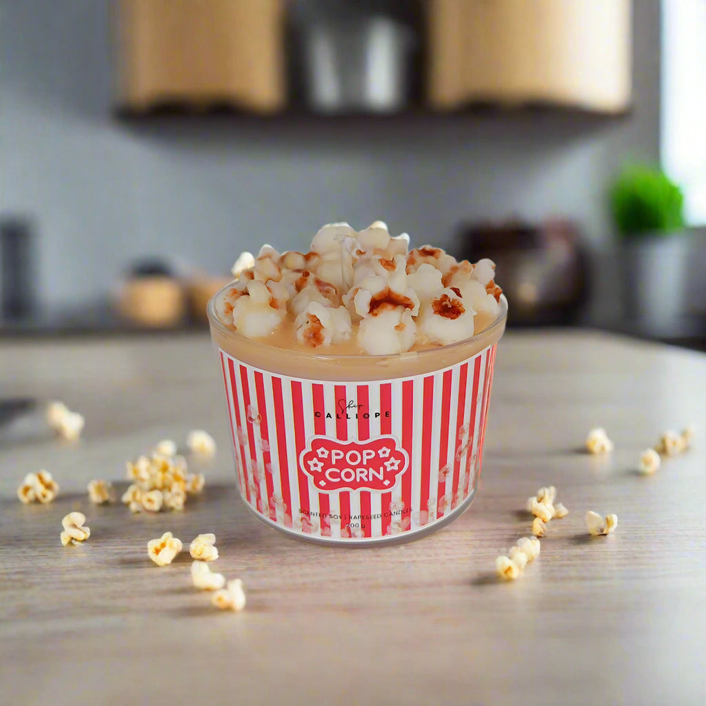 Cup of popcorn with a red and white striped container on a wooden surface.