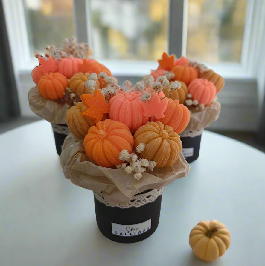 Decorative arrangement of pumpkins in a pot on a white surface.