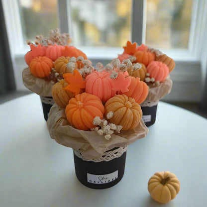 Decorative arrangement of pumpkins in a pot on a white surface.