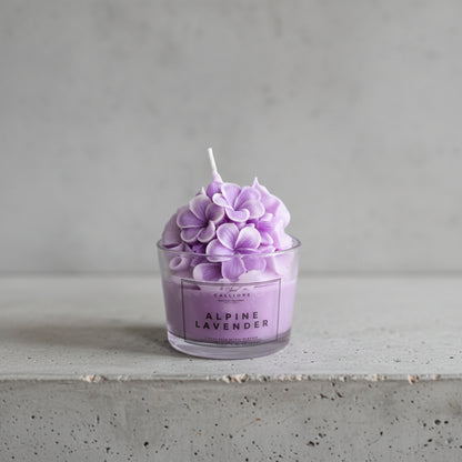 Αρωματικό κερί σόγιας Alpine Lavender με μωβ διακοσμητικά λουλούδια σε διάφανο ποτήρι