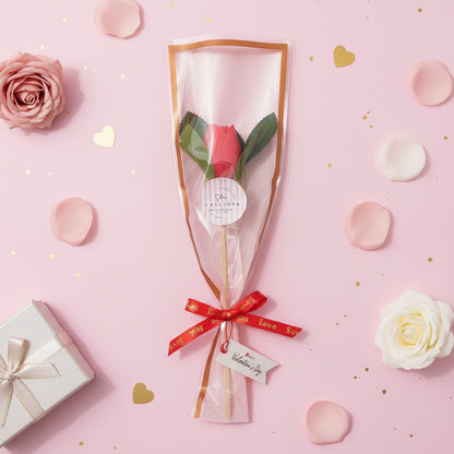 Red tulip wax melt  with red ribbon on a pink background with flowers and gift box.