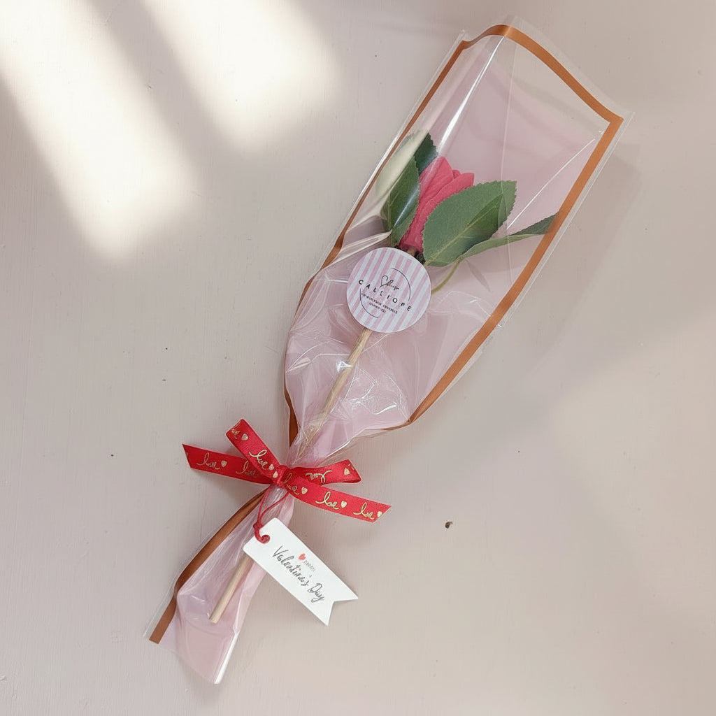 Bouquet of flowers in clear plastic with a red bow and 'Happy Valentine's Day' tag on a light background