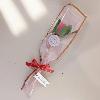Bouquet of flowers in clear plastic with a red bow and 'Happy Valentine's Day' tag on a light background