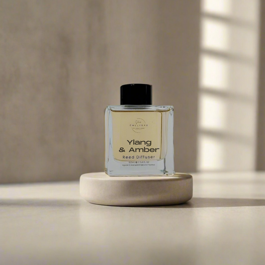 Ylang & Amber reed diffuser on a white pedestal with a neutral background