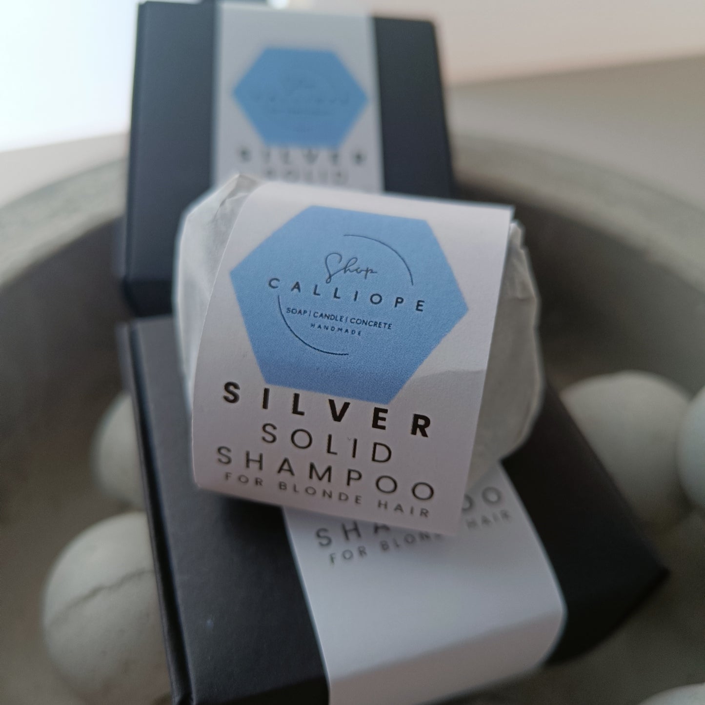 A  solid shampoo bar packaged and labeled as silver solid shampoo for blonde hair