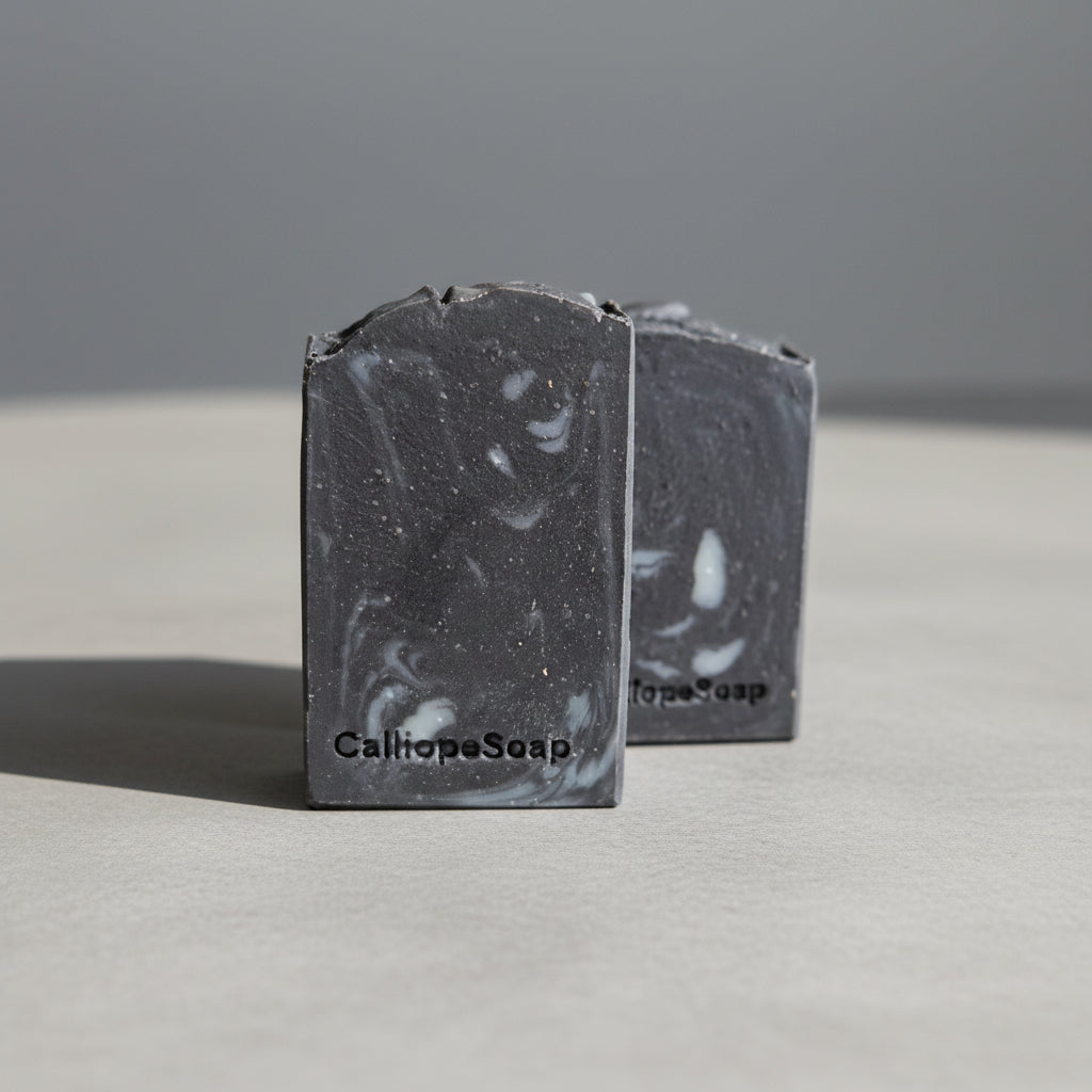 Two bars of Charcoal Soap on a grey surface 