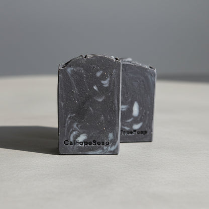 Two bars of Charcoal Soap on a grey surface 