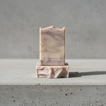 Bar of soap with 'CalliopeSoap' branding on a concrete surface.