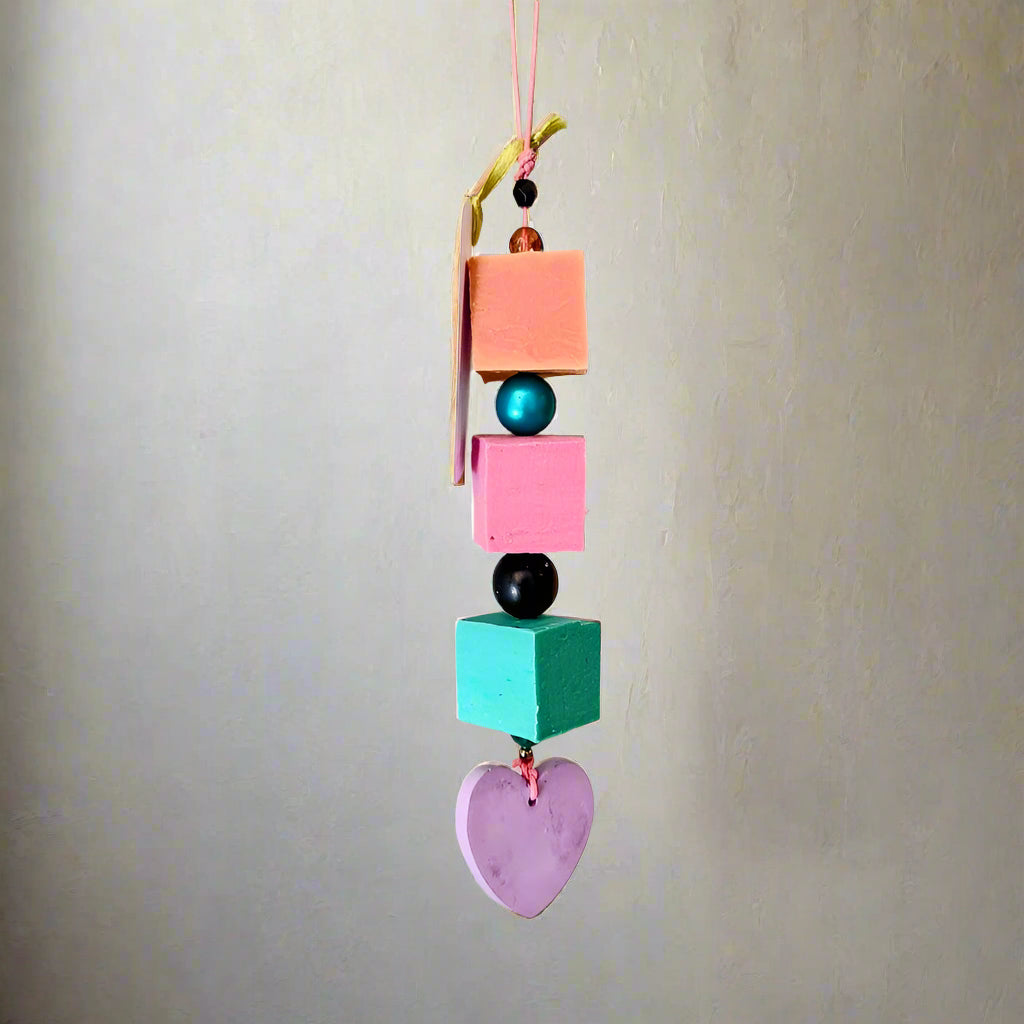 Colorful hanging decorative item with geometric shapes and beads on a plain background