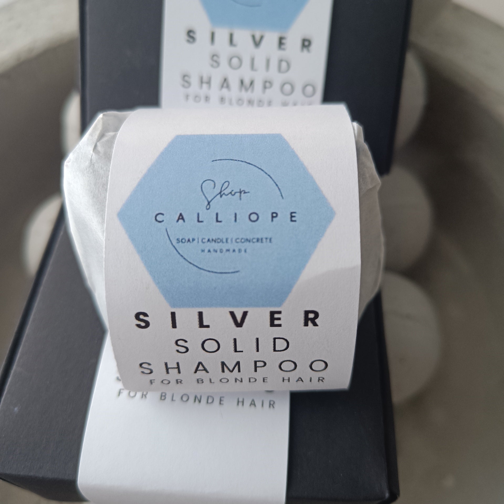 A  solid shampoo bar packaged and labeled as silver solid shampoo for blonde hair