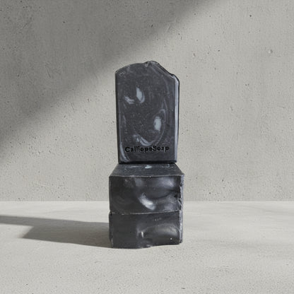 Back charcoal soaps stacked on a light surface with a gray background