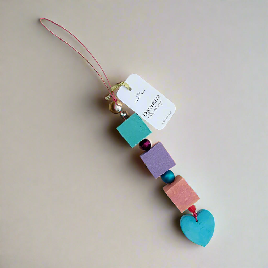Colorful bead charm with a heart-shaped pendant on a string against a light background