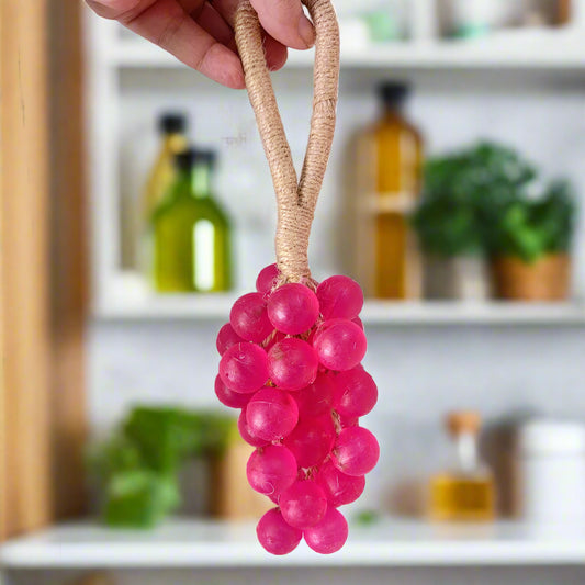 Pink grape-shaped soap held by a hand against a white background